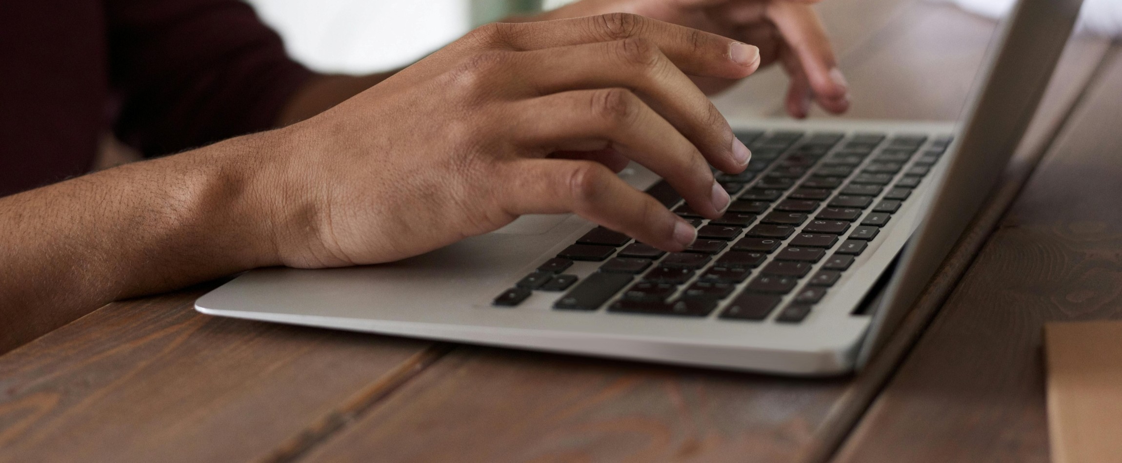 close-up of hands typing on laptop