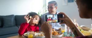 person taking photo of child eating family meal
