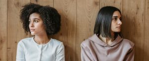 two people leaning against wall staring in opposite directions