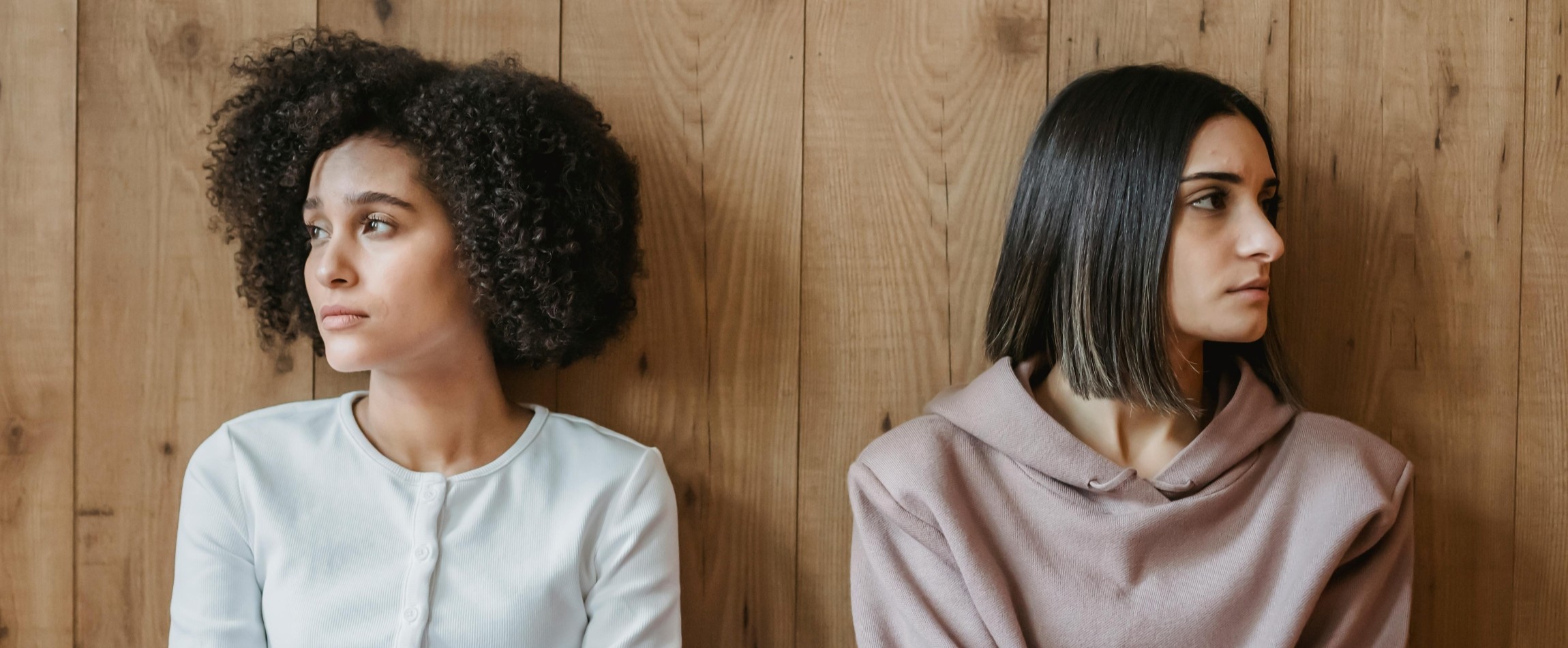two people leaning against wall staring in opposite directions