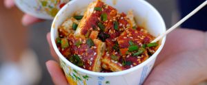 close-up of hand holding cup with tofu dish China