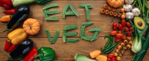 eat veg spelled out in peas on wooden table