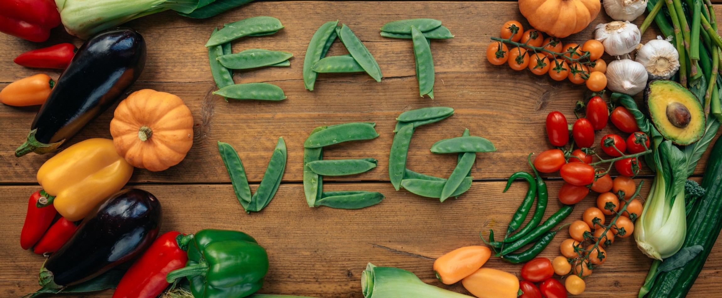 eat veg spelled out in peas on wooden table