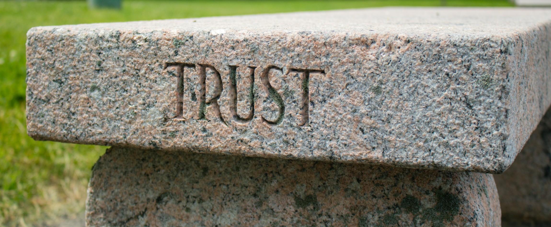 stone bench with word trust carved into side