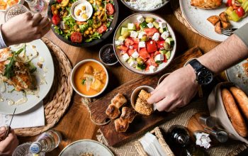 hands reaching across table covered in food view from above
