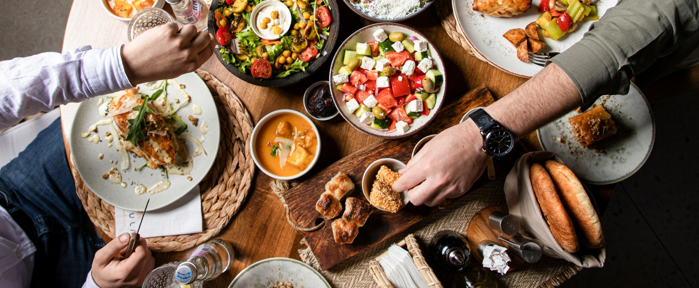 hands reaching across table covered in food view from above