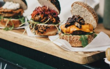 three vegan burgers displayed on wooden board