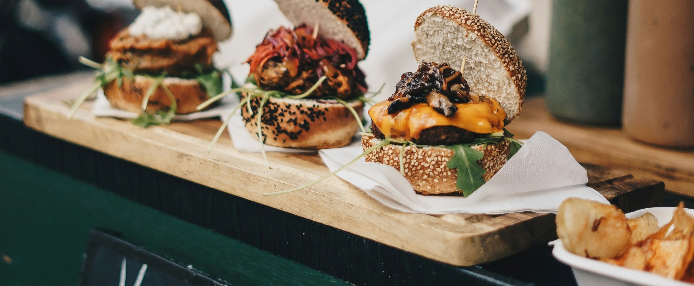 three vegan burgers displayed on wooden board